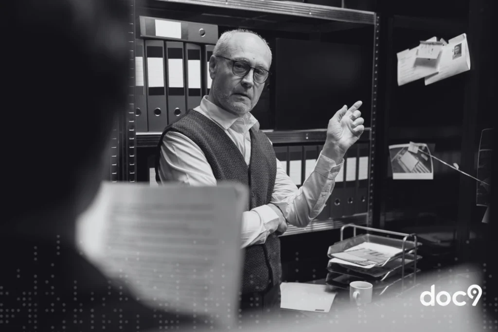 Advogados conversando em uma sala de arquivos, representando serviços forenses.