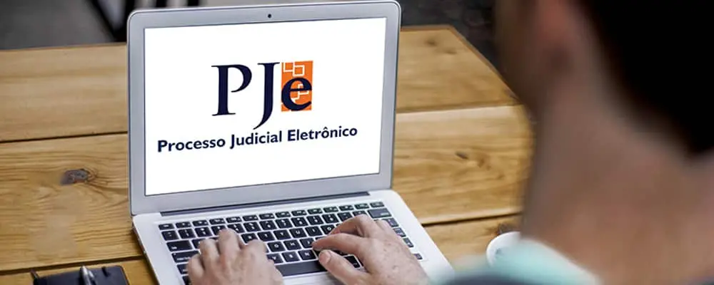 Pessoas acessando cópias do processo judicial pelo notebook, na tela, uma imagem que representa o PJ-e