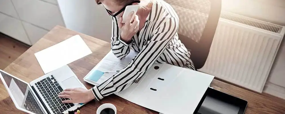 Pessoa falando ao telefone enquanto organiza cópias de processo juducial