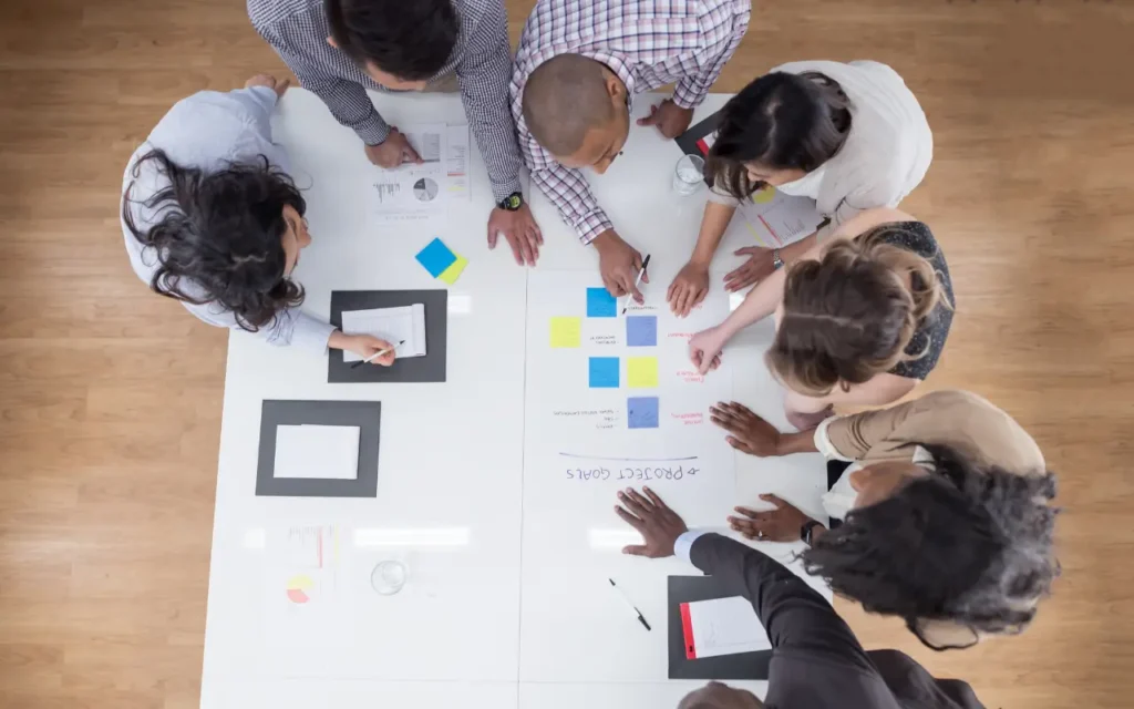 Grupo de pessoas reunidas em uma mesa mapeando seu fluxo de trabalho