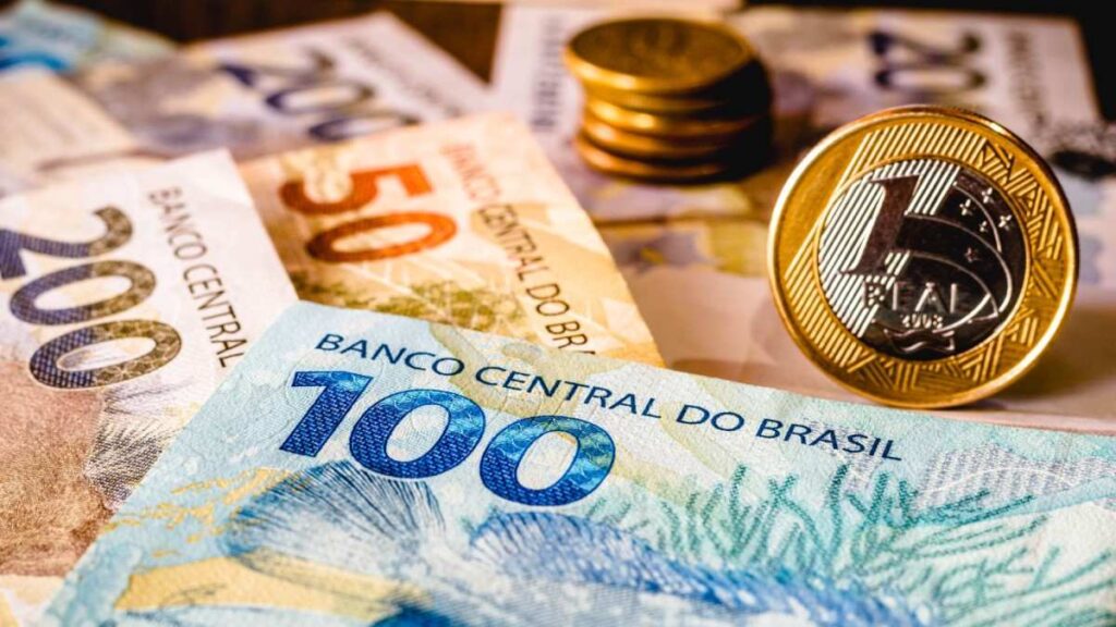 Cédulas e moedas brasileiras, incluindo notas de 100, 50 e 200 reais, e uma moeda de 1 real em destaque