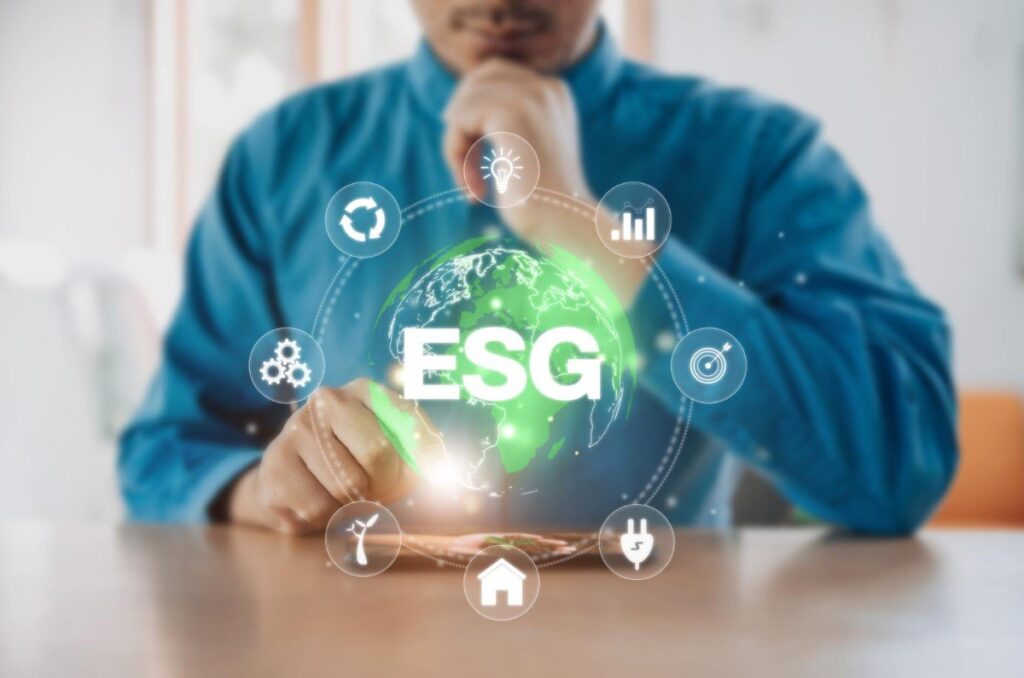 Homem de camisa azul interage com ícones digitais de ESG (Environmental, Social, and Governance) projetados sobre um globo holográfico verde, simbolizando práticas empresariais sustentáveis.