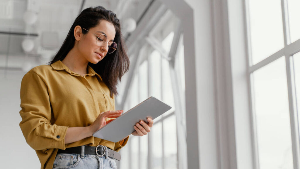 Mulher segurando um tablet, concentrada em seu trabalho.