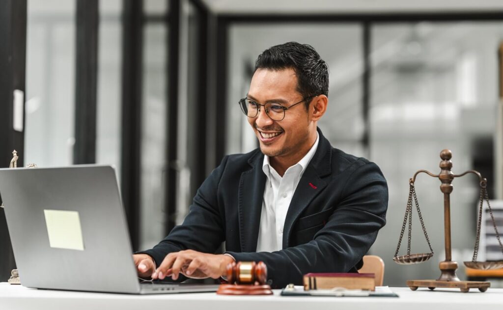 Homem de óculos sorrindo e trabalhando em um notebook
