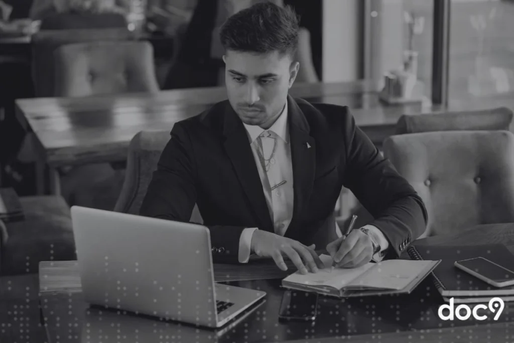 Advogado sentado fazendo anotações em um caderno e olhando para o notebook, representando o ChatGPT jurídico.