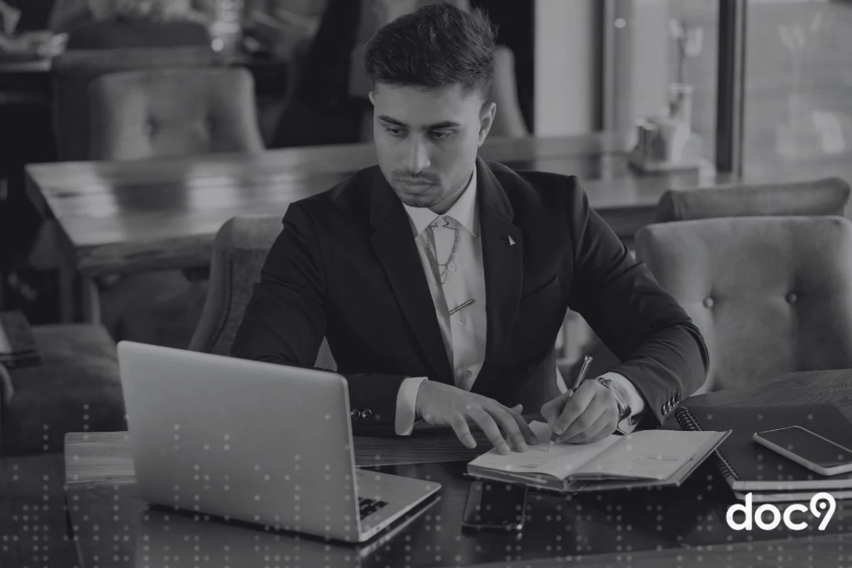 Advogado sentado fazendo anotações em um caderno e olhando para o notebook, representando o ChatGPT jurídico.