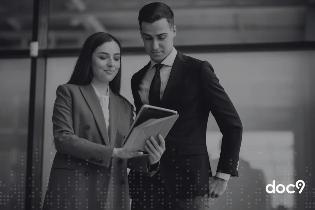 Advogados em pé olhando para um tablet, representando a gestão do processo litigioso.