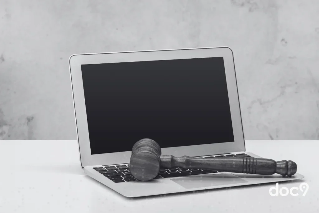 Martelo sobre notebook em uma mesa branca, representando softwares jurídicos.