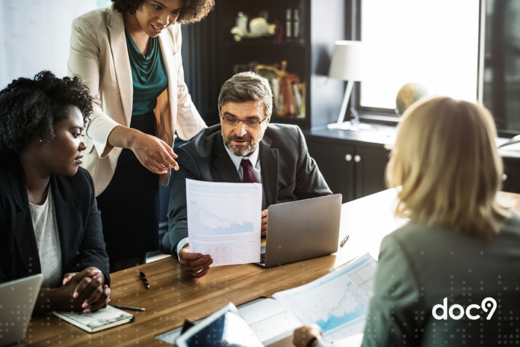 Alguns advogados estão em um escritório, reunidos sobre uma mesa, com documentos em mãos, representando a correspondência jurídica.