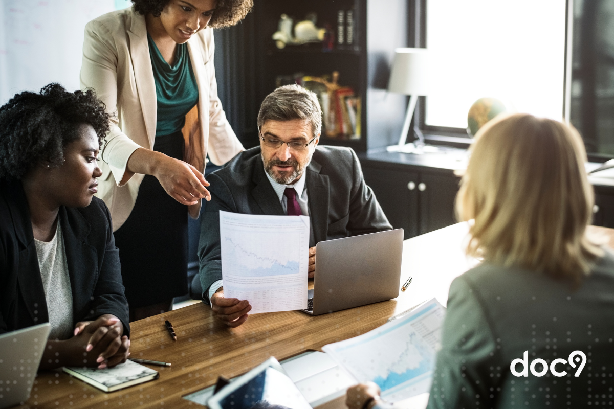 Alguns advogados estão em um escritório, reunidos sobre uma mesa, com documentos em mãos, representando a correspondência jurídica.