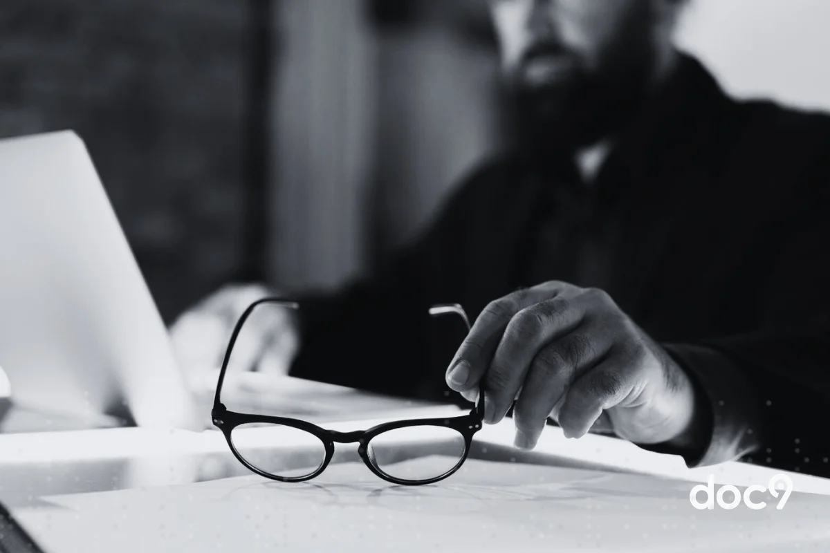 Imagem empreto e branco de um homem segurando um óculos de grau com a mão esquerda, enquanto lê um documento, representando um artigo sobre advocacia moderna em 2026 da doc9.