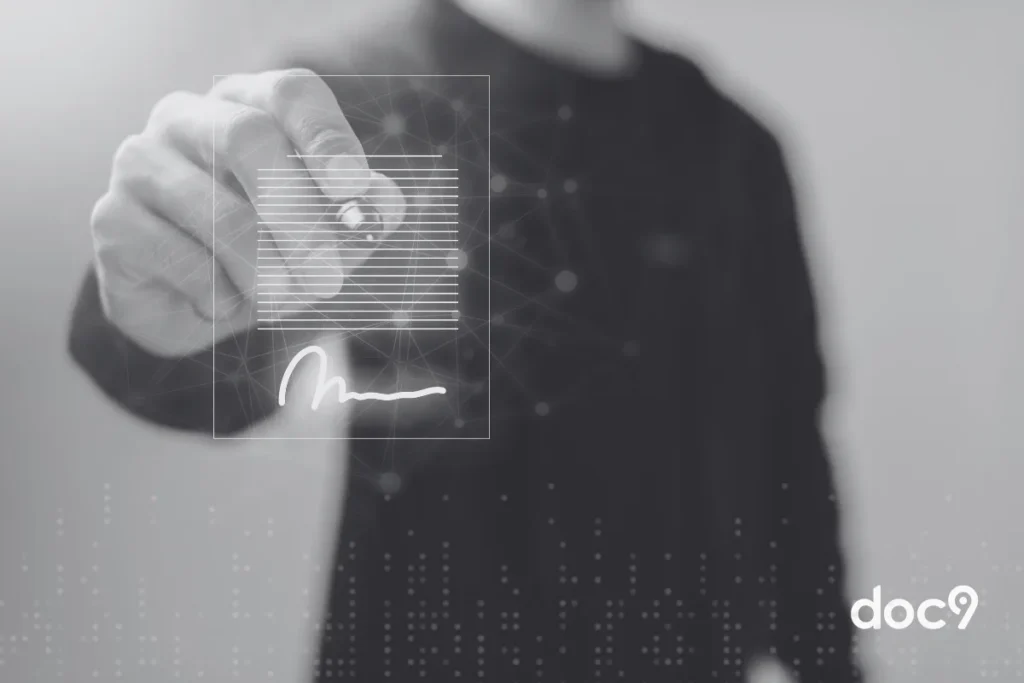 Uma mão masculina segura uma caneta no ar, enquanto assina documento com certificado digital, ilustrando artigo da doc9.