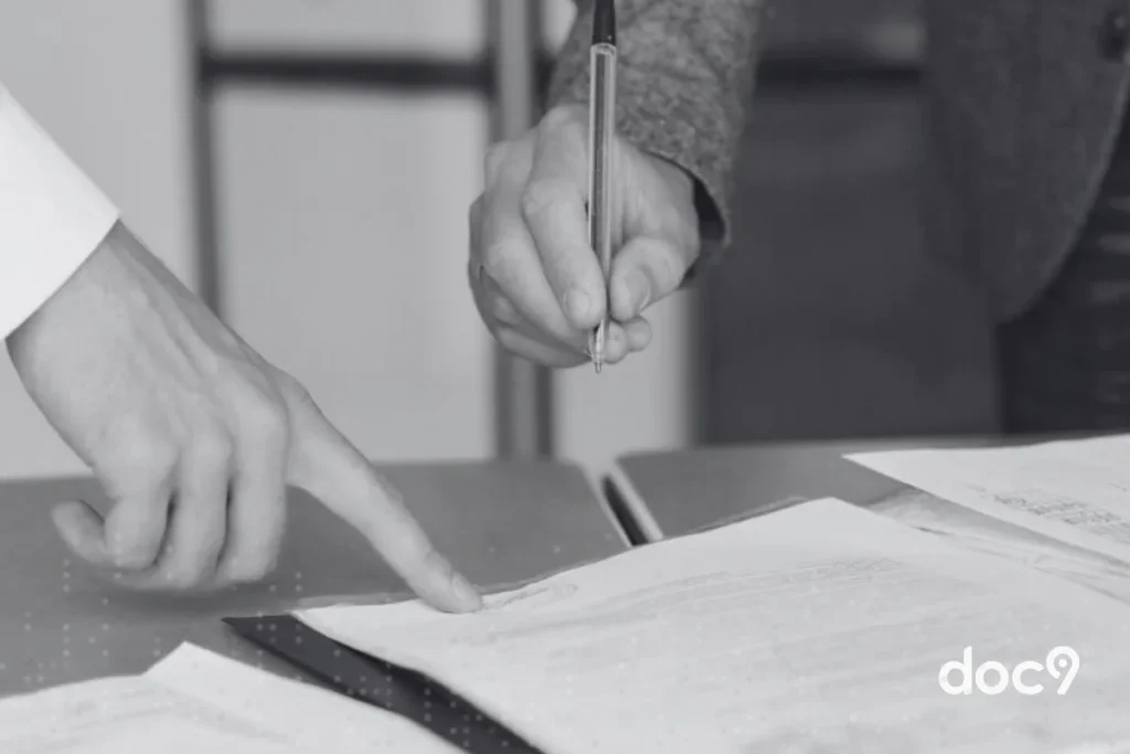 Mãos de duas pessoas revisando e assinando documentos em uma mesa, ilustrando um artigo sobre audiência trabalhista da doc9.